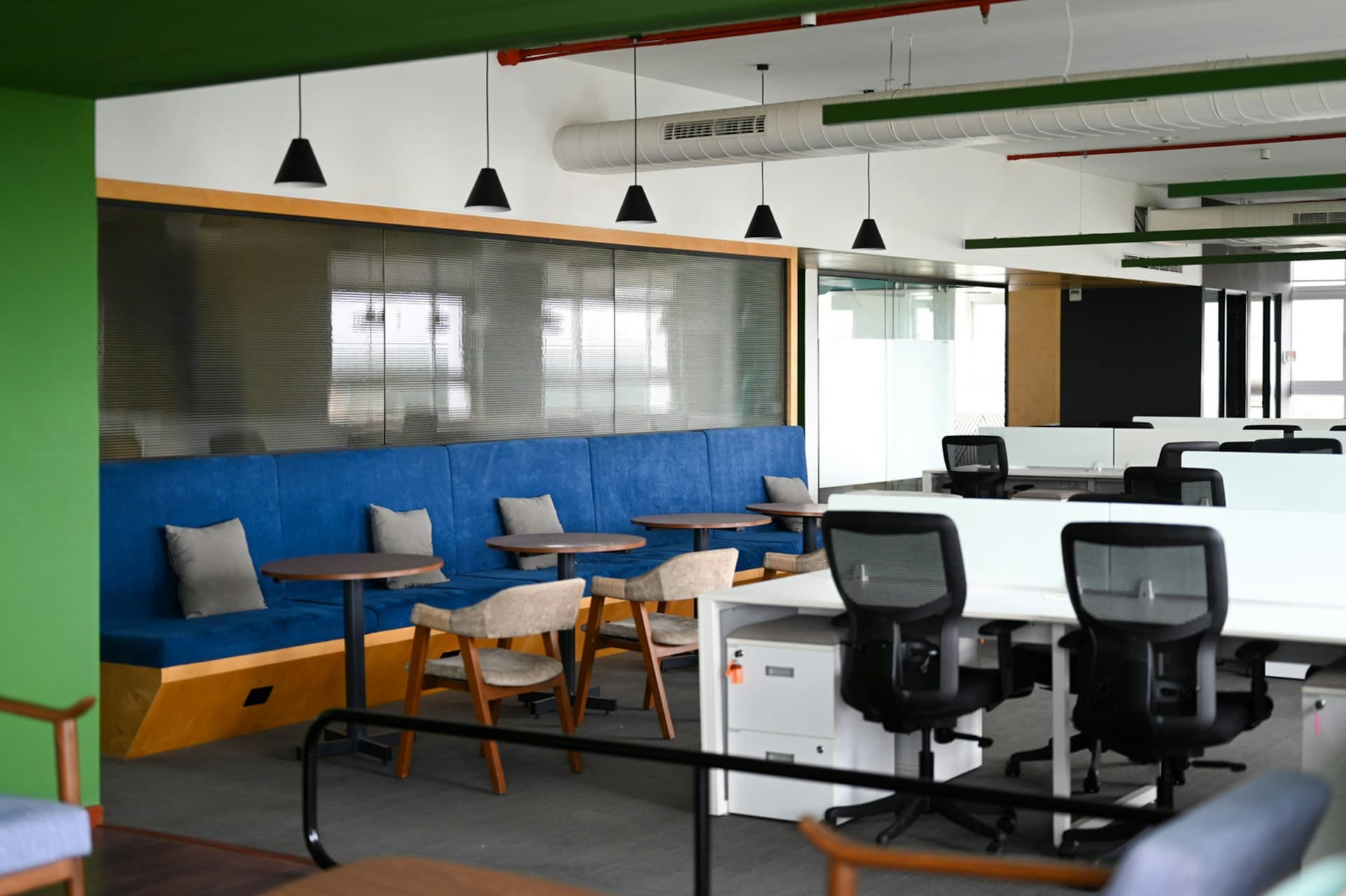 A coworking floor: desks and chairs beside a long bench under the windows